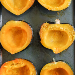 roasted acorn squash halves on a baking sheet pan