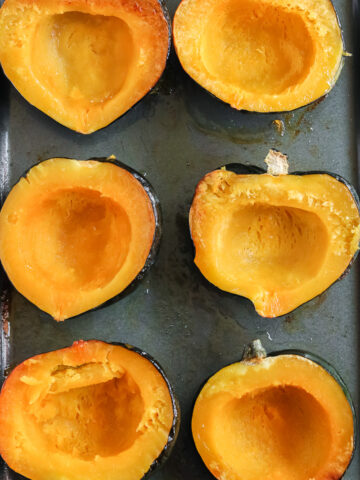 roasted acorn squash halves on a baking sheet pan