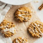 pumpkin oatmeal cookies on unbleached parchment paper styled next to a plate with more cookies