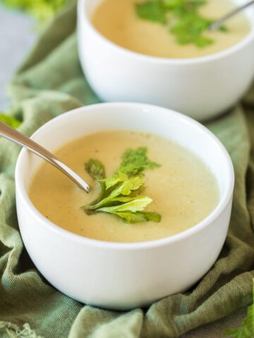 vegan cream of celery soup in white bowls on a green napkin