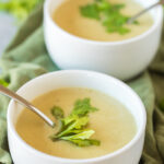 cream of celery soup in white bowls on a green napkin
