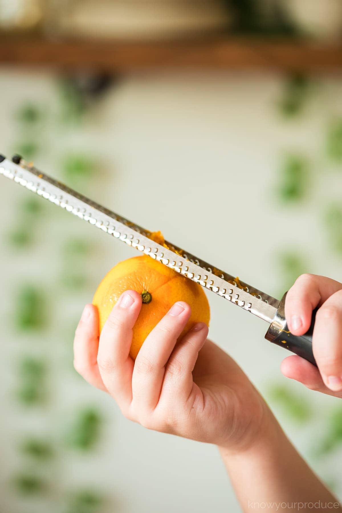 hands holding an orange and zesting an orange