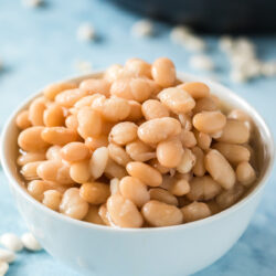 cooked instant pot white beans in a white bowl with instant pot in background