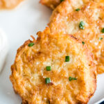 close up photo of potato latkes on a white plate with navy blue napkin underneath the plate