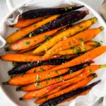 overhead photo of roasted rainbow carrots in a white casserole dish with handles