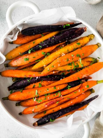 overhead photo of roasted rainbow carrots in a white casserole dish with handles
