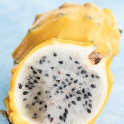 yellow dragon fruit cut in half showing inside with another dragon fruit behind it