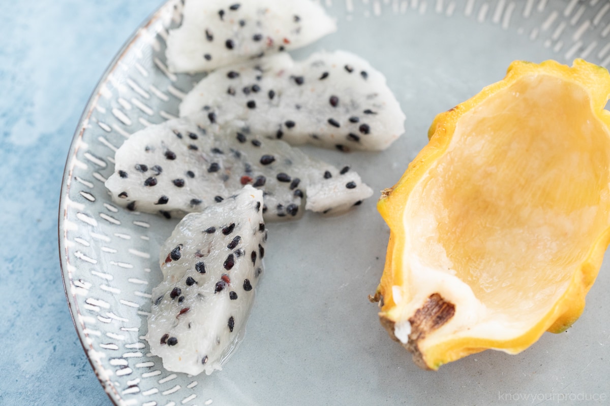 yellow dragon fruit sliced up on a plate with empty dragon fruit skin to the right