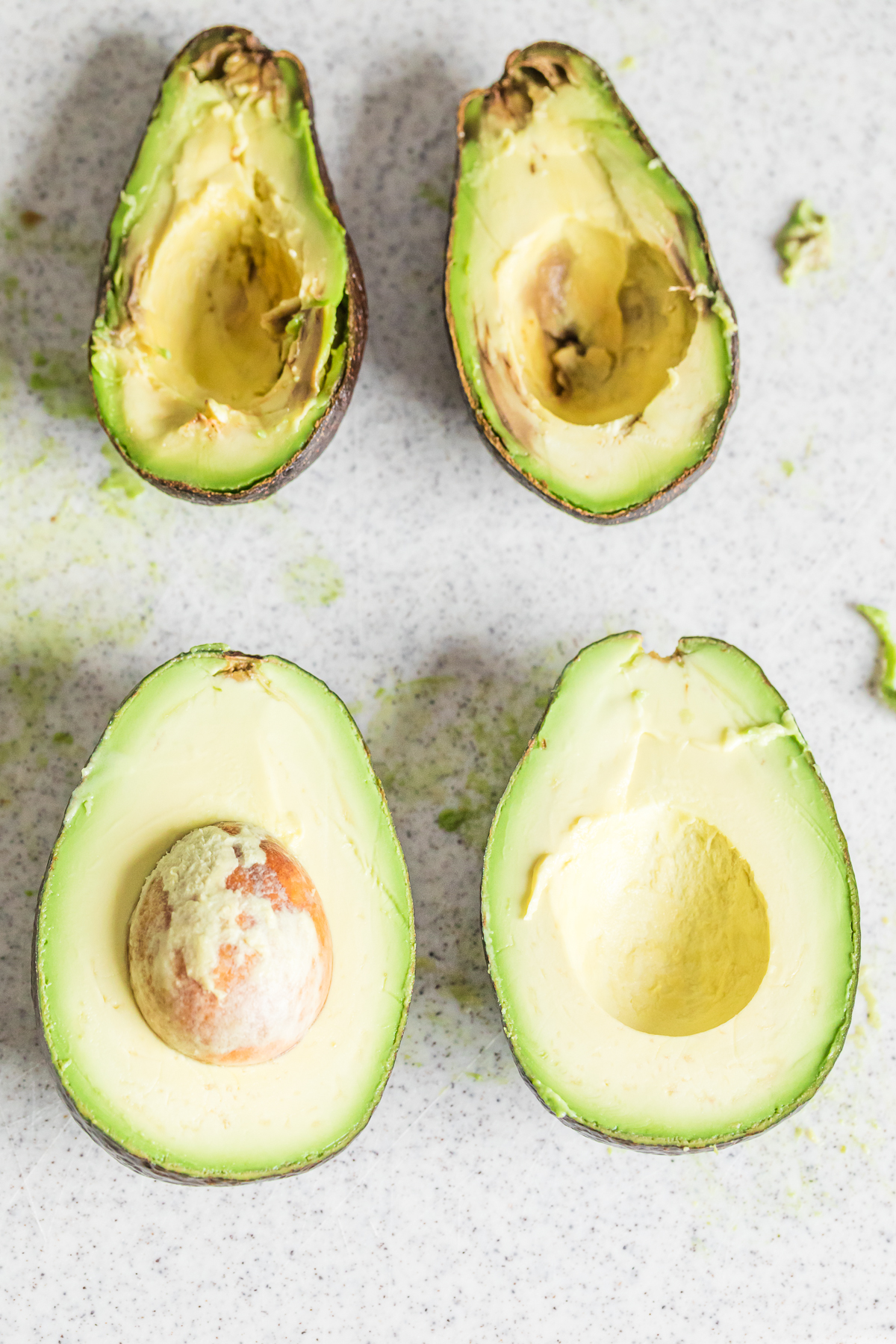 fresh avocados cut in half showing a ripe avocado and overripe avocado