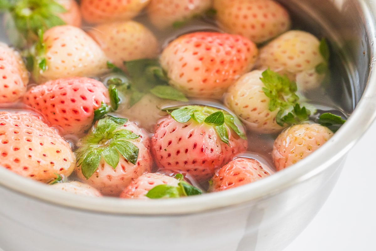 pineberries in a stainless steel bowl with water to wash.
