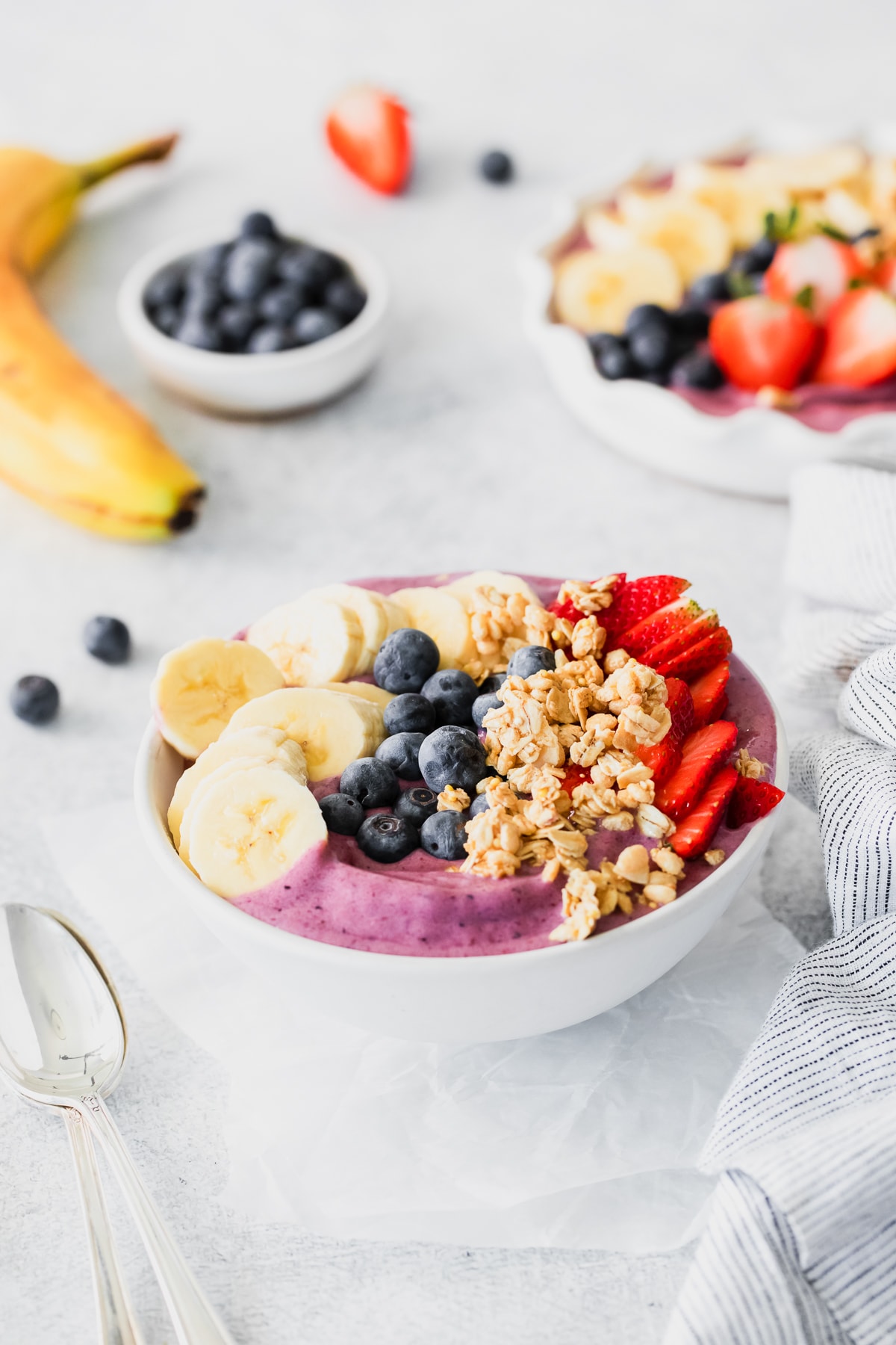 acai bowl topped with sliced banana, granola, blueberries, and sliced strawberries.