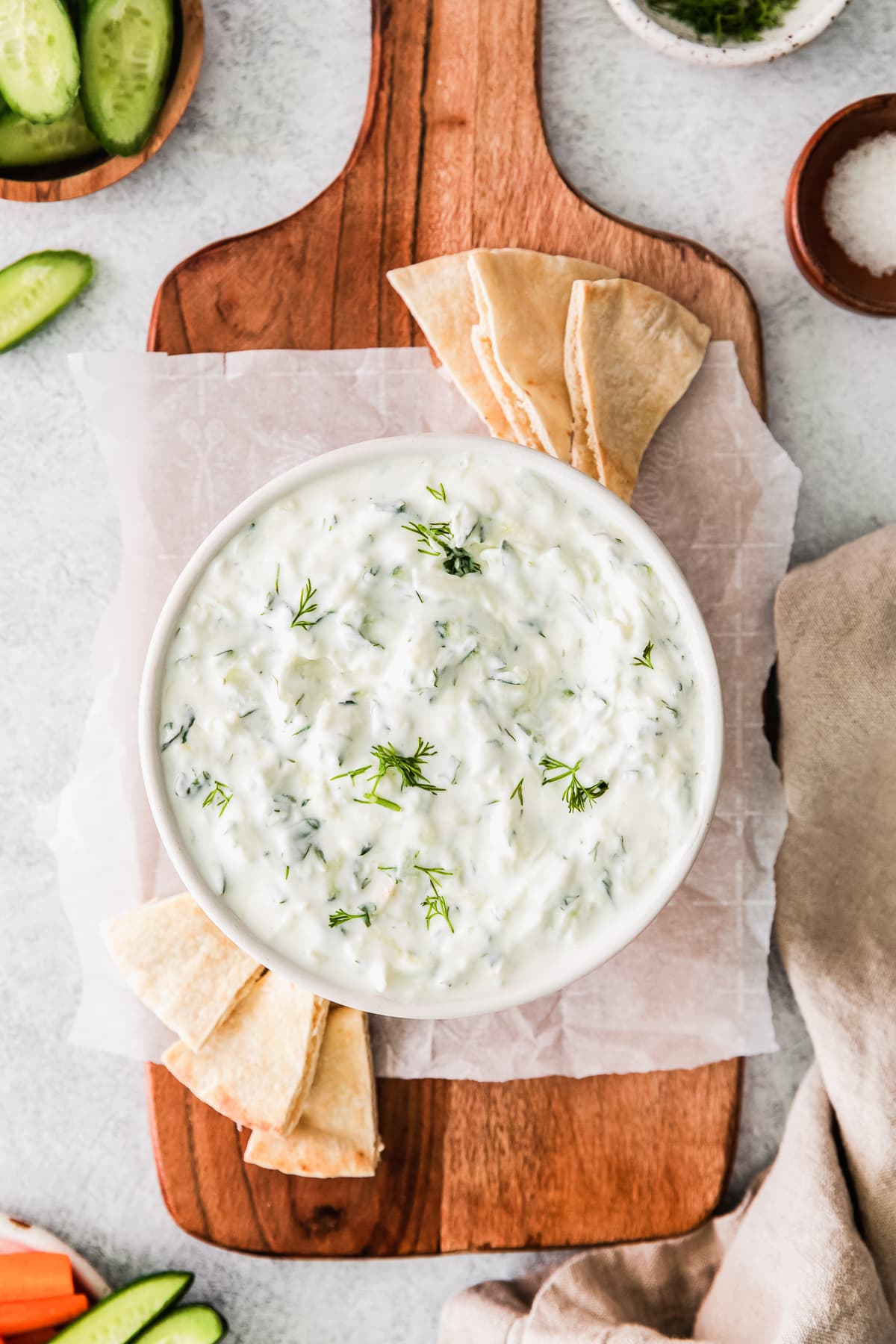tzatziki sauce in a white bowl with pita on the side.