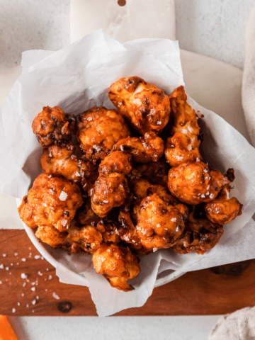 air fryer cauliflower wings in a white bowl with parchment paper.