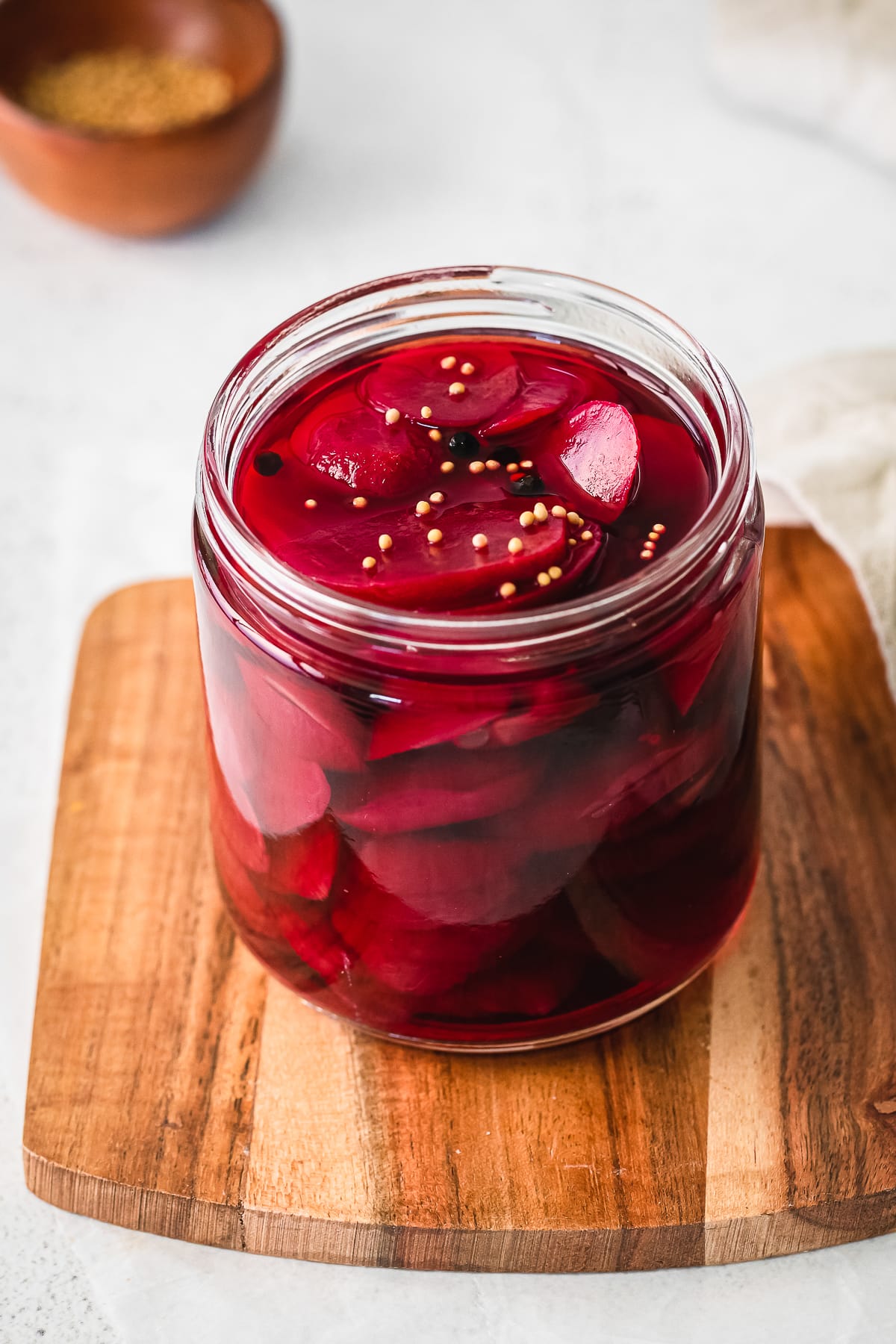 quick pickled beets in a glass jar on a wooden board.
