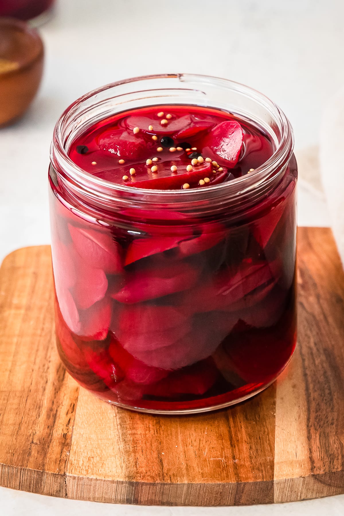 close up of quick pickled beets in a glass jar on a cutting board.