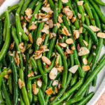 green beans almondine on a white platter.