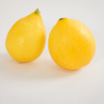 1 tear drop yellow limequat and one rounded limequat also yellow on white background.