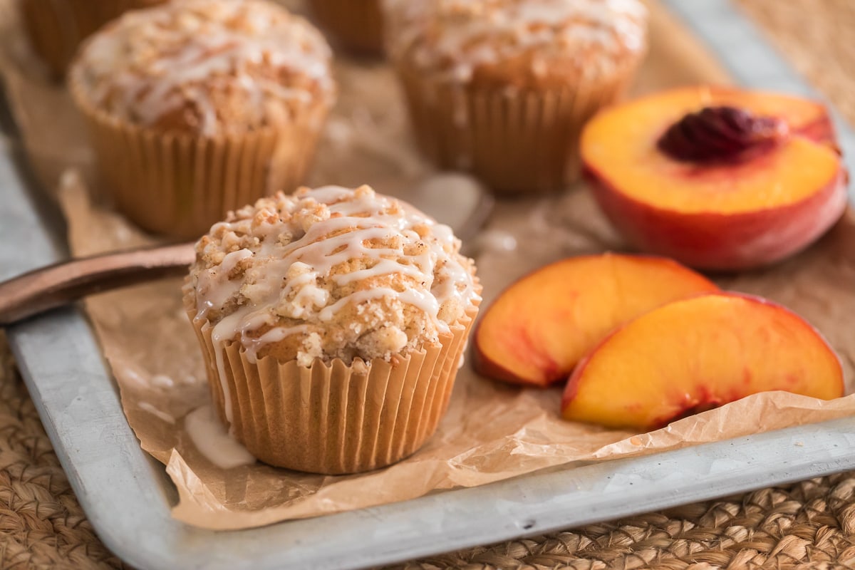peach muffins with crumb topping and vanilla glaze drizzle.