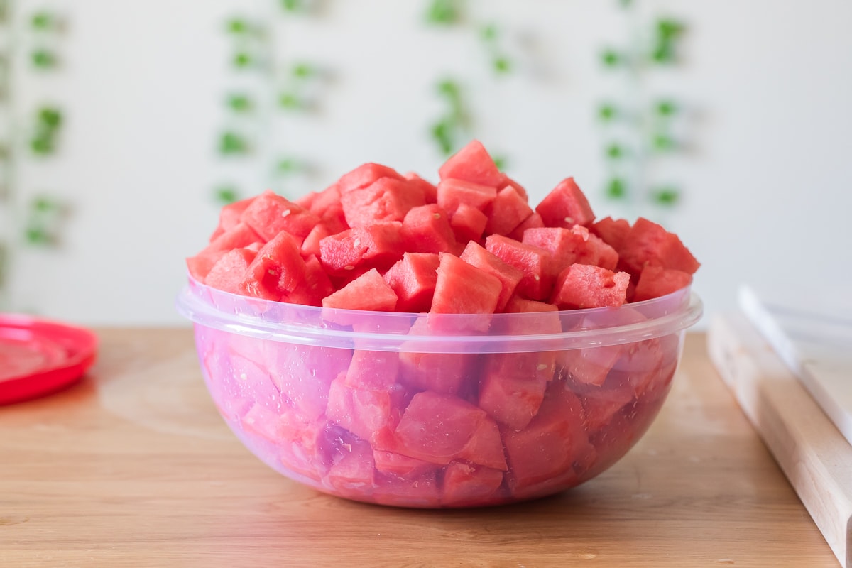 watermelon chunks in a large plastic bowl on a table.