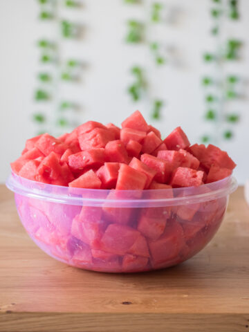 how to cut a watermelon showing watermelon chunks in a large bowl.