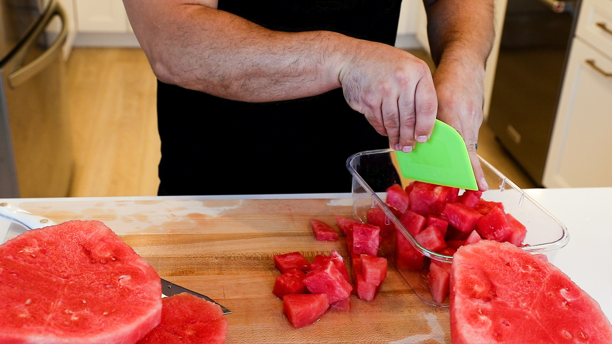 scooping watermelon chunks into container.
