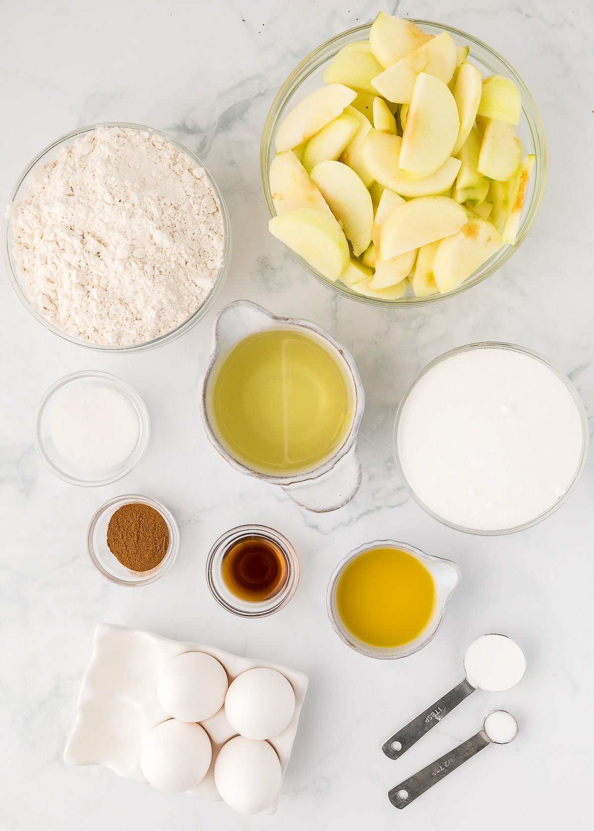 overhead photo on ingredients in bowls and cups for Jewish apple cake.