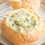 homemade bread bowl on plate with creamy soup inside.