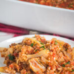 cabbage roll casserole on a white plate with the casserole dish behind it.