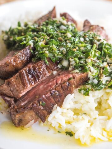 chimichurri steak close up photo with it over white rice.