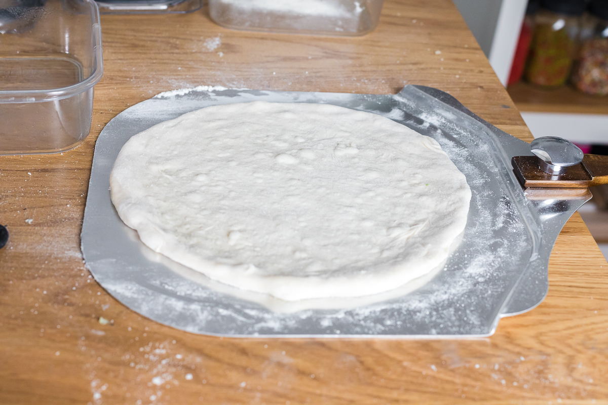 pizza dough stretched out on a pizza peel.