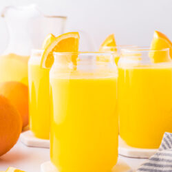 homemade orangeade recipe in a glasses with an orange wedge on the rim.