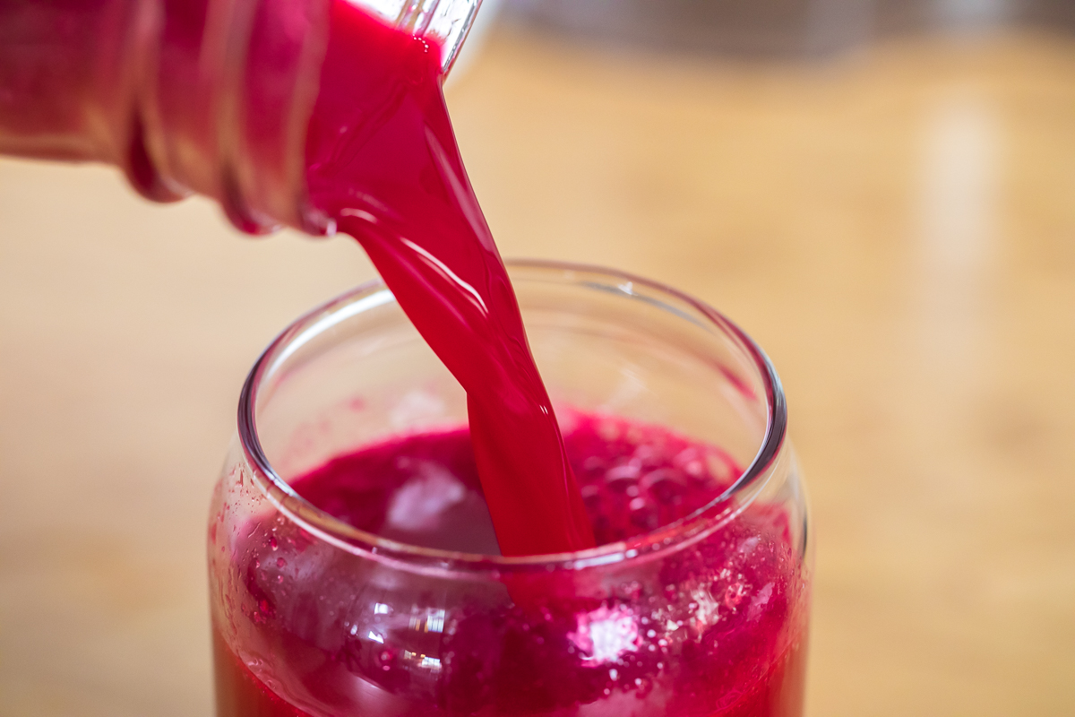 pouring beet juice into a glass.