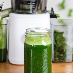 green juice in a large mason jar with nama j2 juicer behind it.