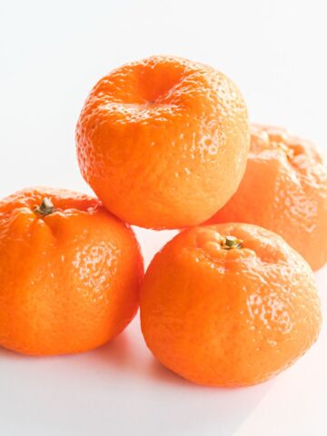 4 kishu mandarins stacked on a white background.