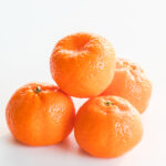 4 kishu mandarins stacked on a white background.