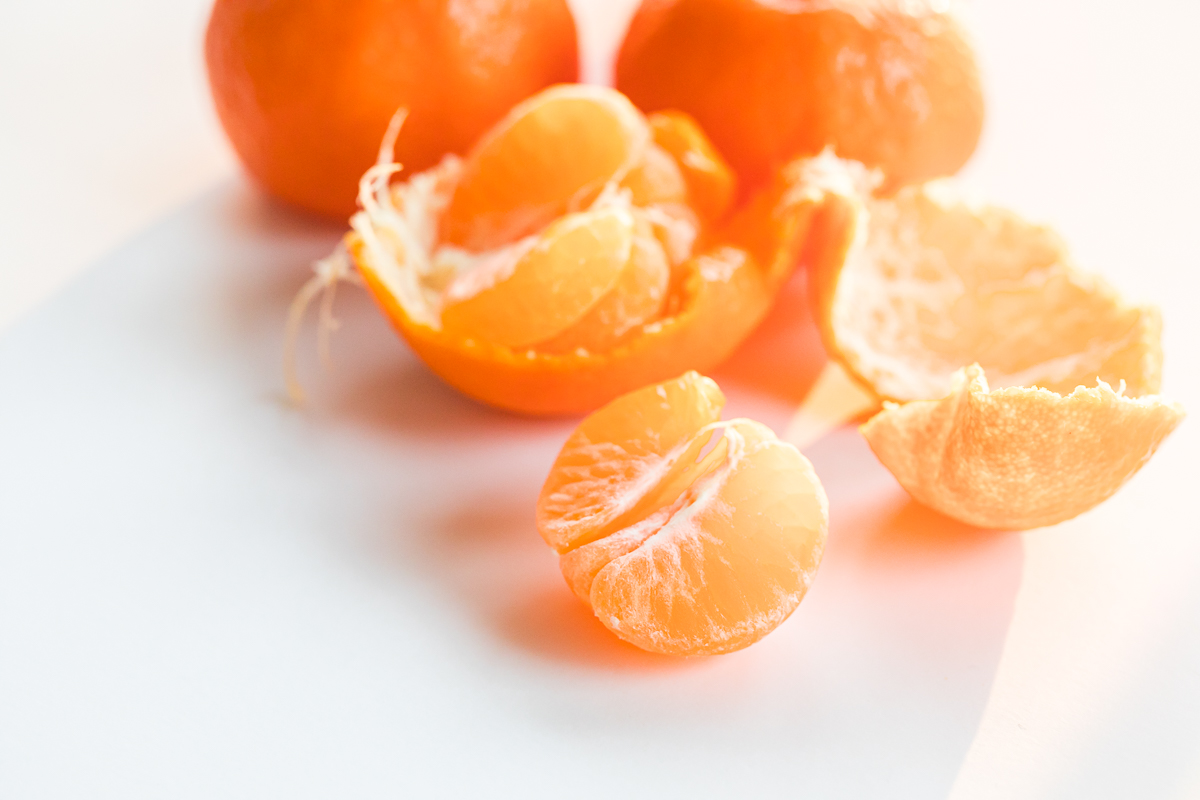 kishu mandarin half on a white background with mandarins and peel behind it.
