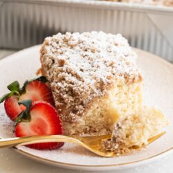 sourdough crumb cake on a dessert plate with a gold fork that has a bite of cake on it.