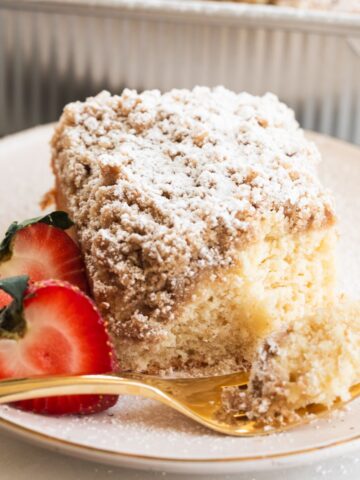 sourdough crumb cake on a dessert plate with a gold fork that has a bite of cake on it.
