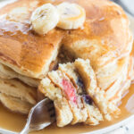 Sourdough discard pancakes on a plate with a fork full of pancake in the front of the plate.