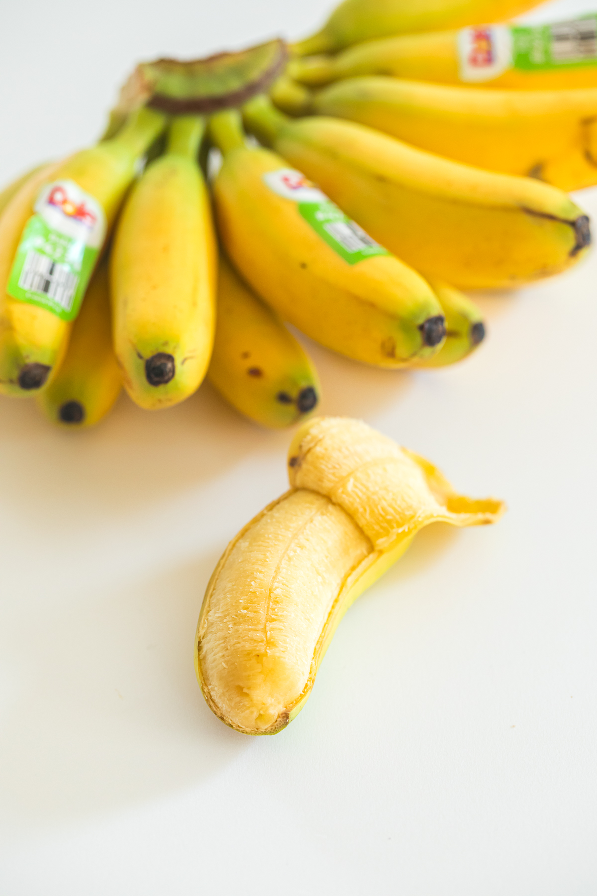 partially peeled baby banana and a bunch of baby bananas above it.