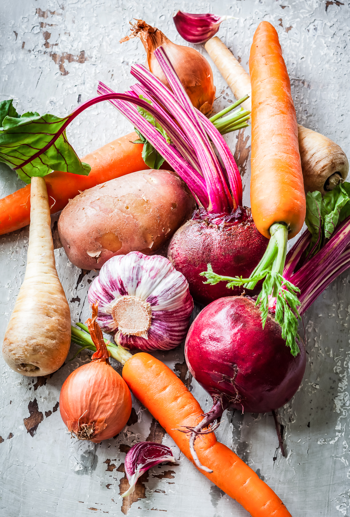 Assorted root vegetables arranged on top of each other on a gray slate slab.