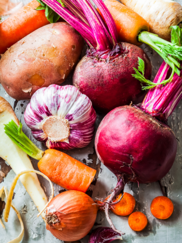 Assorted root vegetables on a gray slate backdrop.