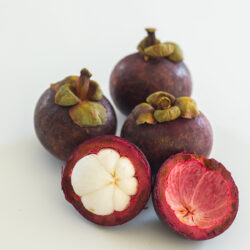 4 mangosteen with one being sliced open to show segments and inside.