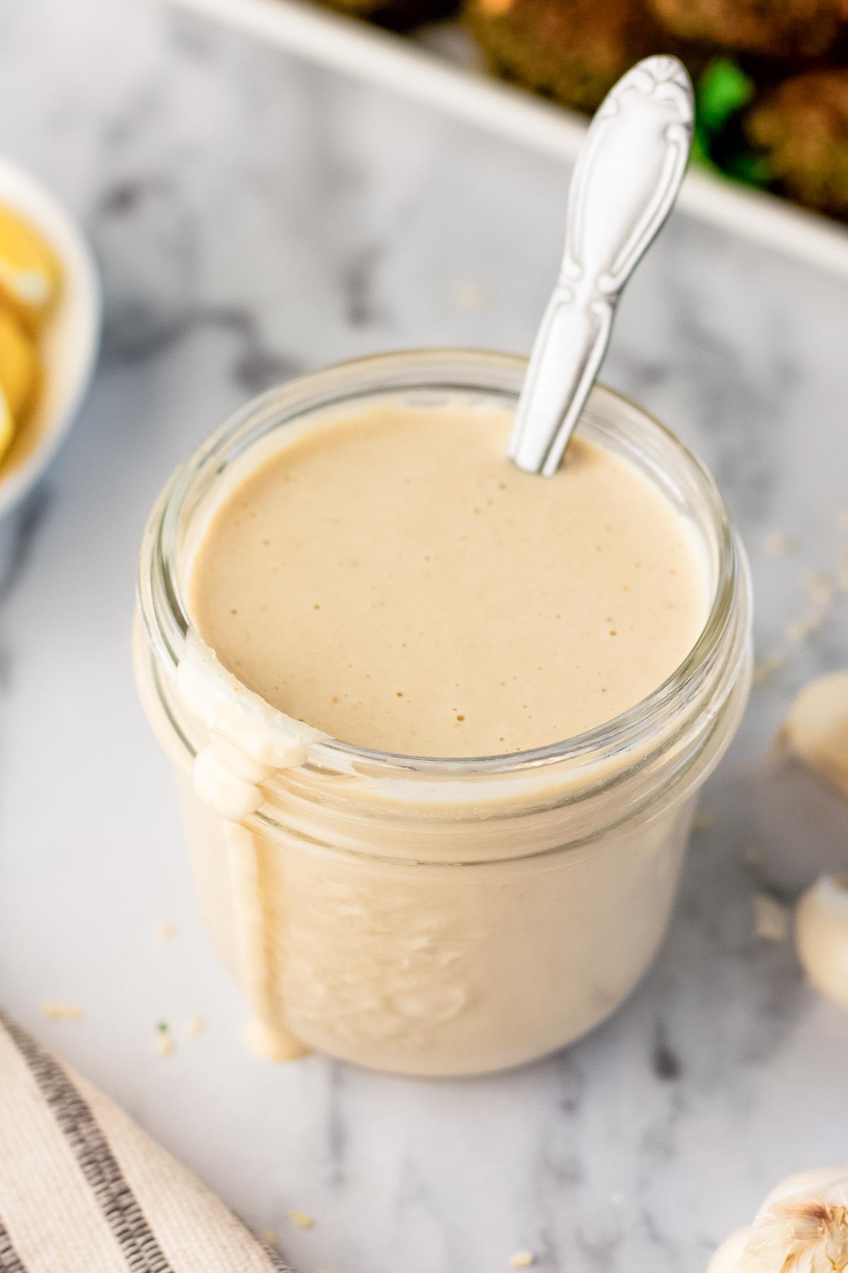 tahini sauce in a glass mason jar with a spoon in it.