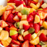 easy fruit salad or pineapple, strawberries, apples, and kiwi in a serving bowl.