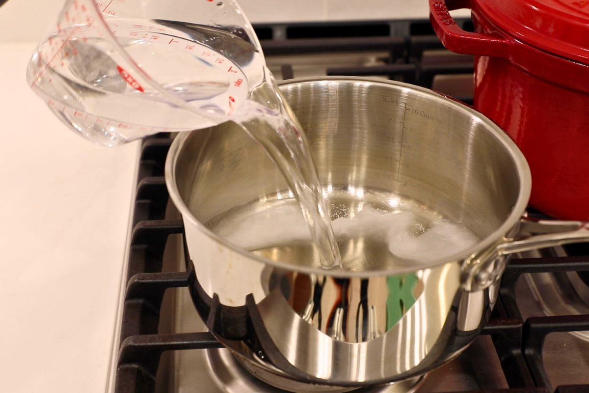 pouring water into pot, making brine in saucepan for pickles.