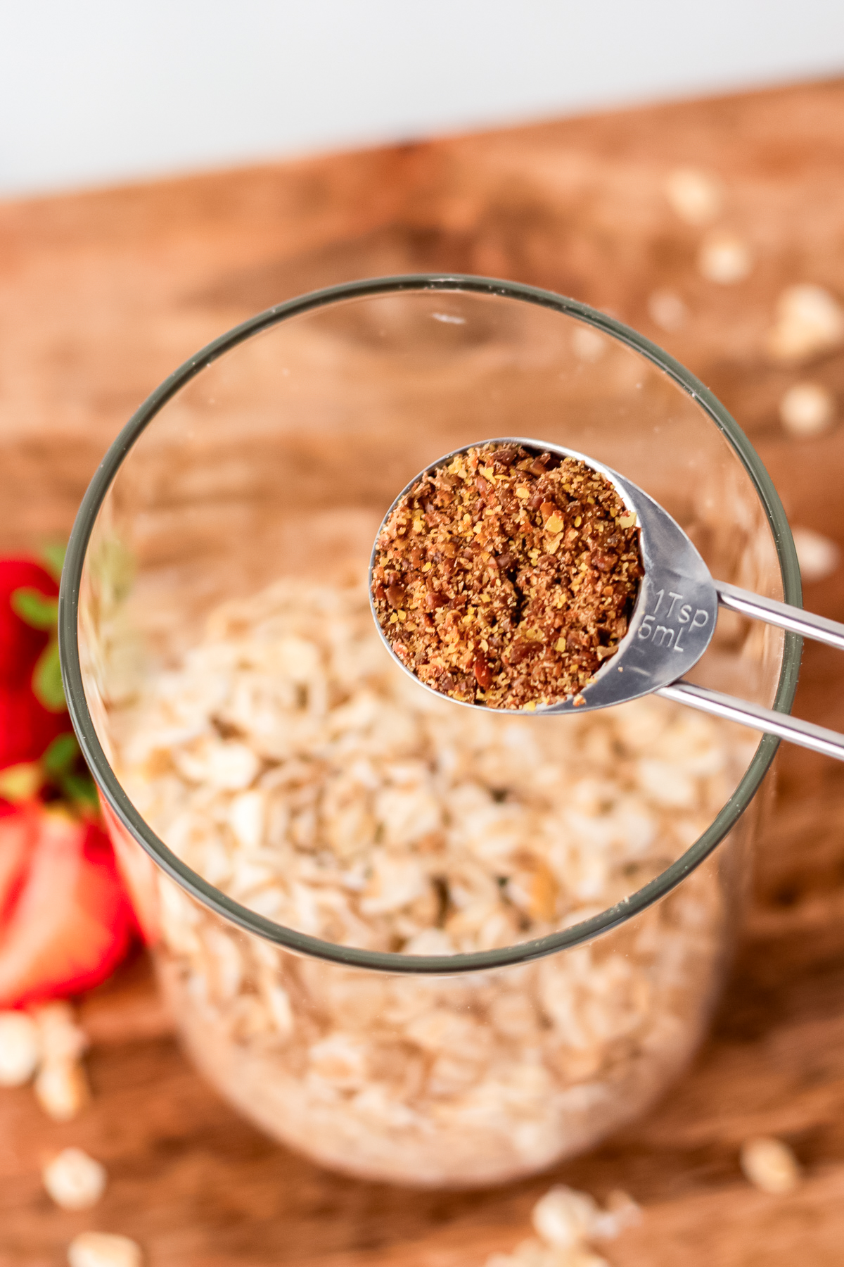 ground flaxseed in measuring spoon overtop of rolled oats.