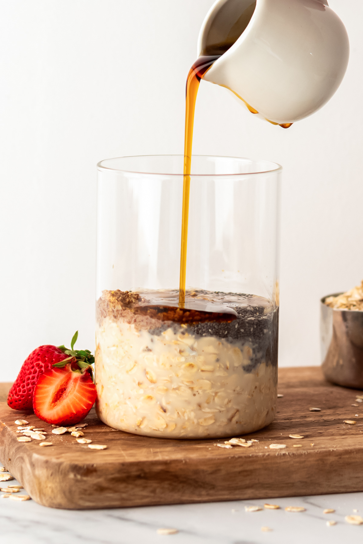 hand pouring maple syrup into glass jar.