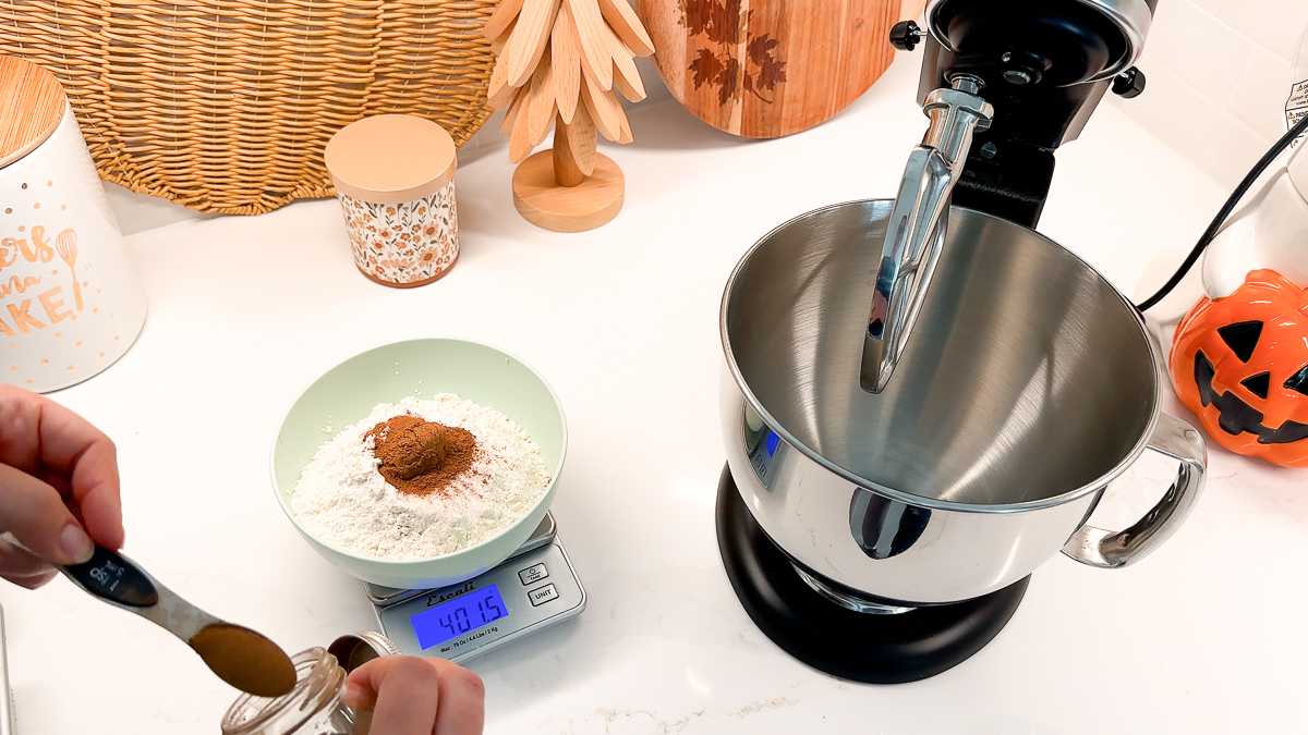 measuring dry ingredients on scale and adding cinnamon.