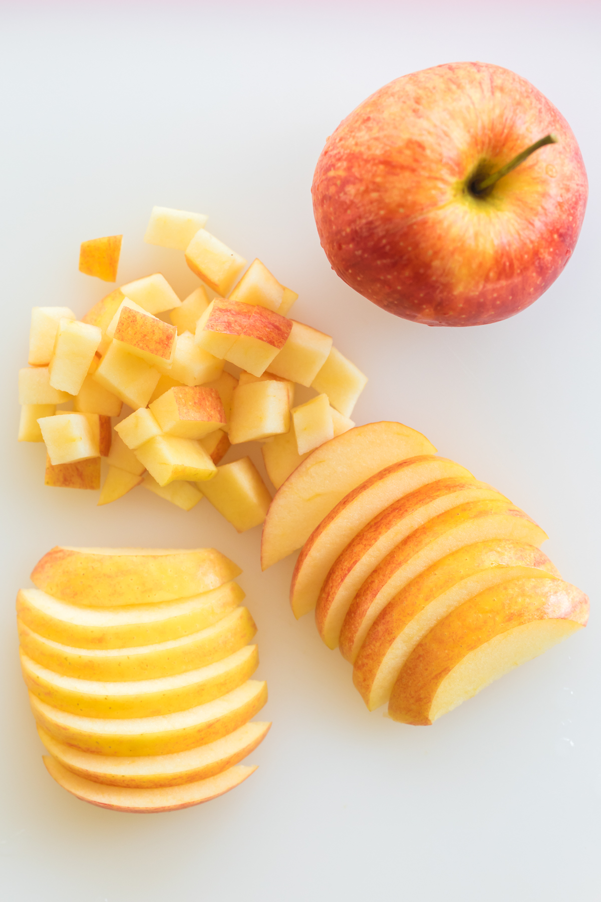 how to cut an apple, apple slices, diced apple and whole apple on a cutting board.